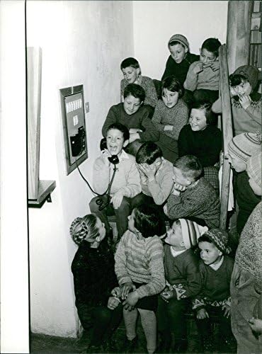 Vintage fotografija malog dječaka koji razgovara telefonom dok ga drugi gledaju i smiju mu se u Lavaredu.- 1963